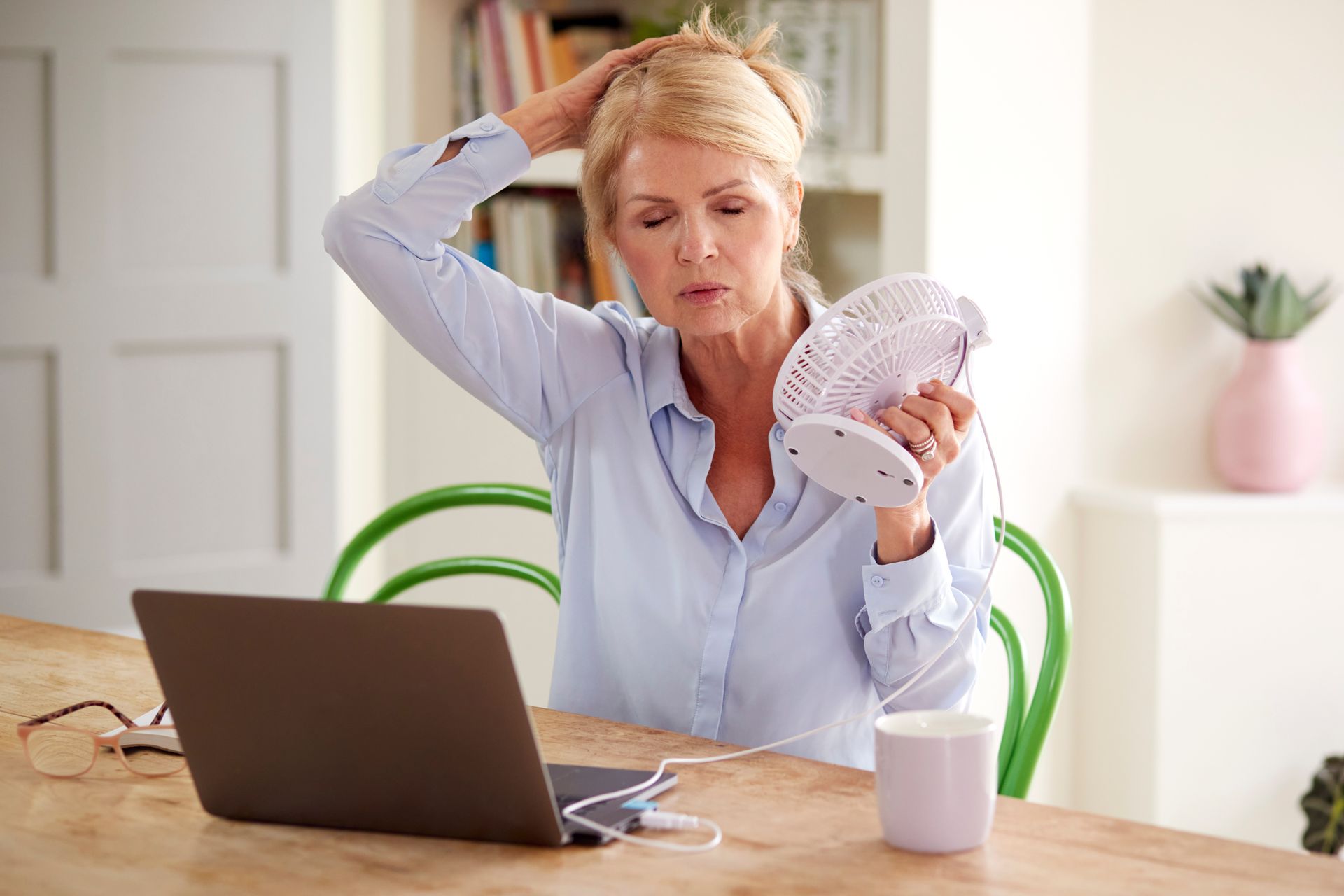 A woman with menopause is cooling herself with a fan. A woman with menopause is cooling herself with a fan.
