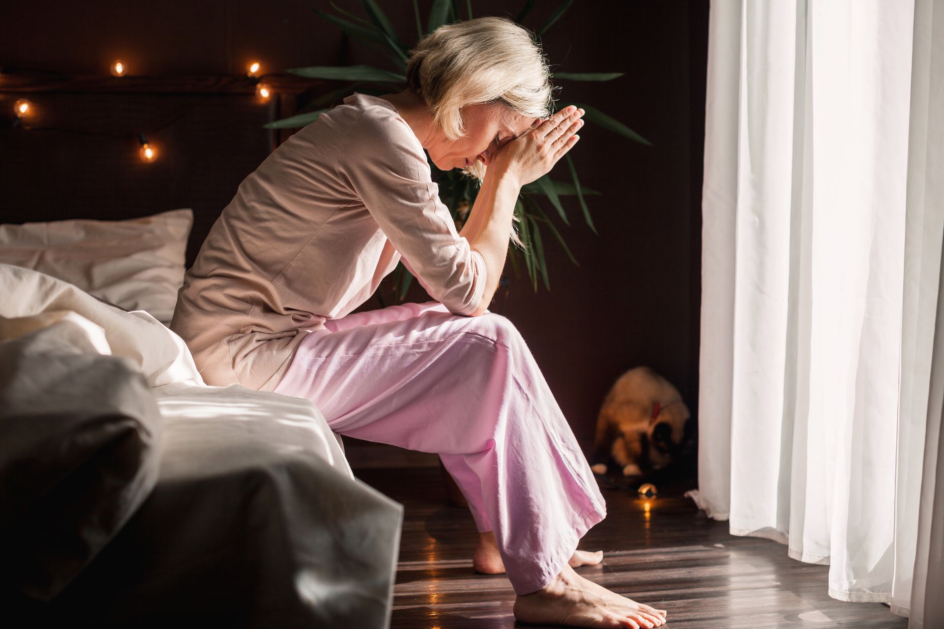 A woman is sitting on a bed without being able to sleep. A woman is sitting on a bed without being able to sleep.