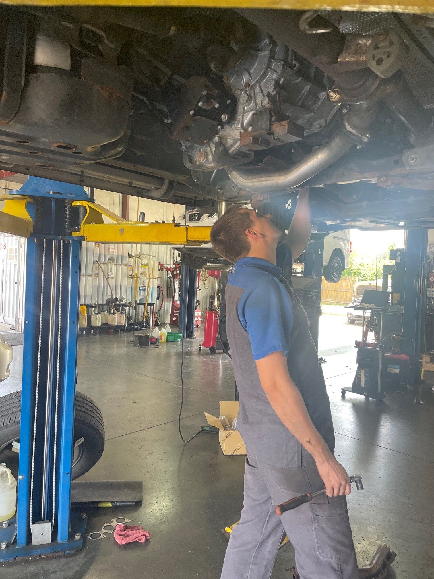 Mechanic inspecting the underside of a car on a lift in an auto repair shop