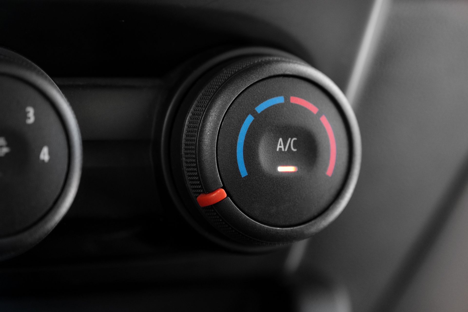 Close-up of a car climate control dial with blue and red temperature markings and A/C label