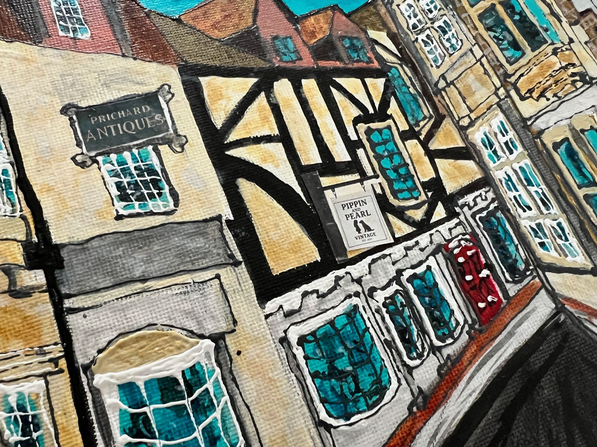 Watercolor painting of a street with shops; tan and black timber-framed buildings, teal windows, angled perspective.