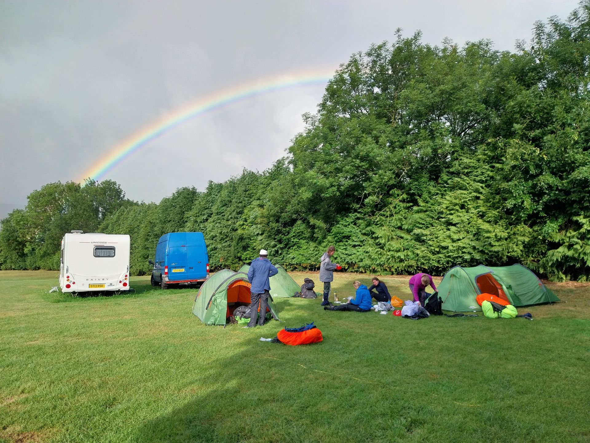 A group of people are sitting under a tent in a field.