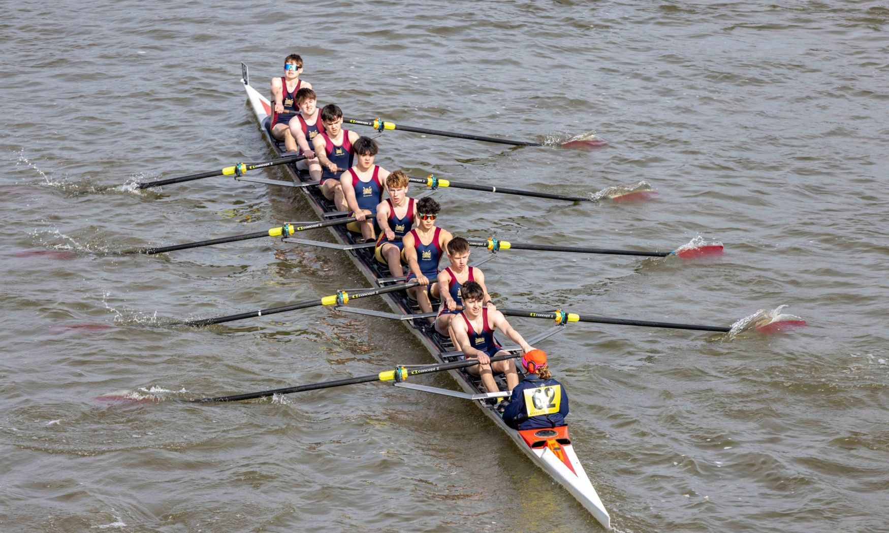 A group of people are rowing a boat on a river.