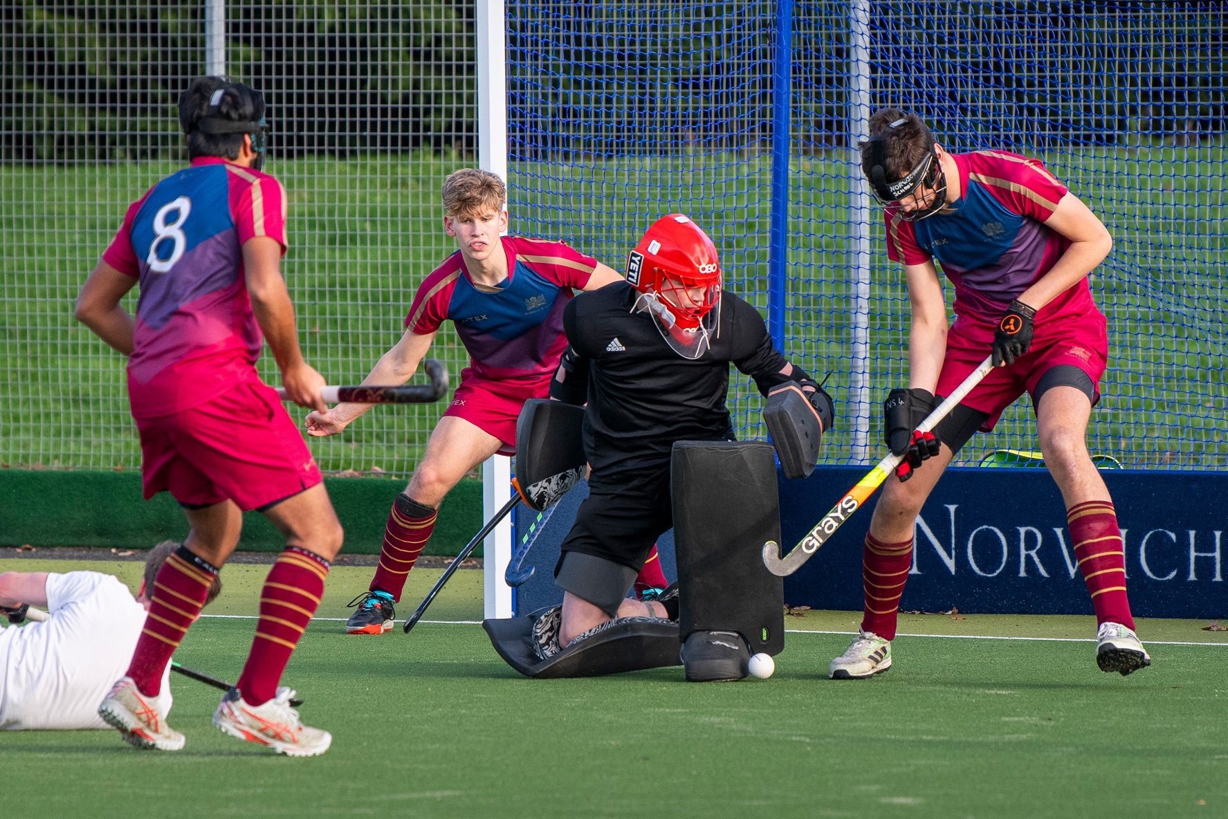 A group of men are playing field hockey on a field.