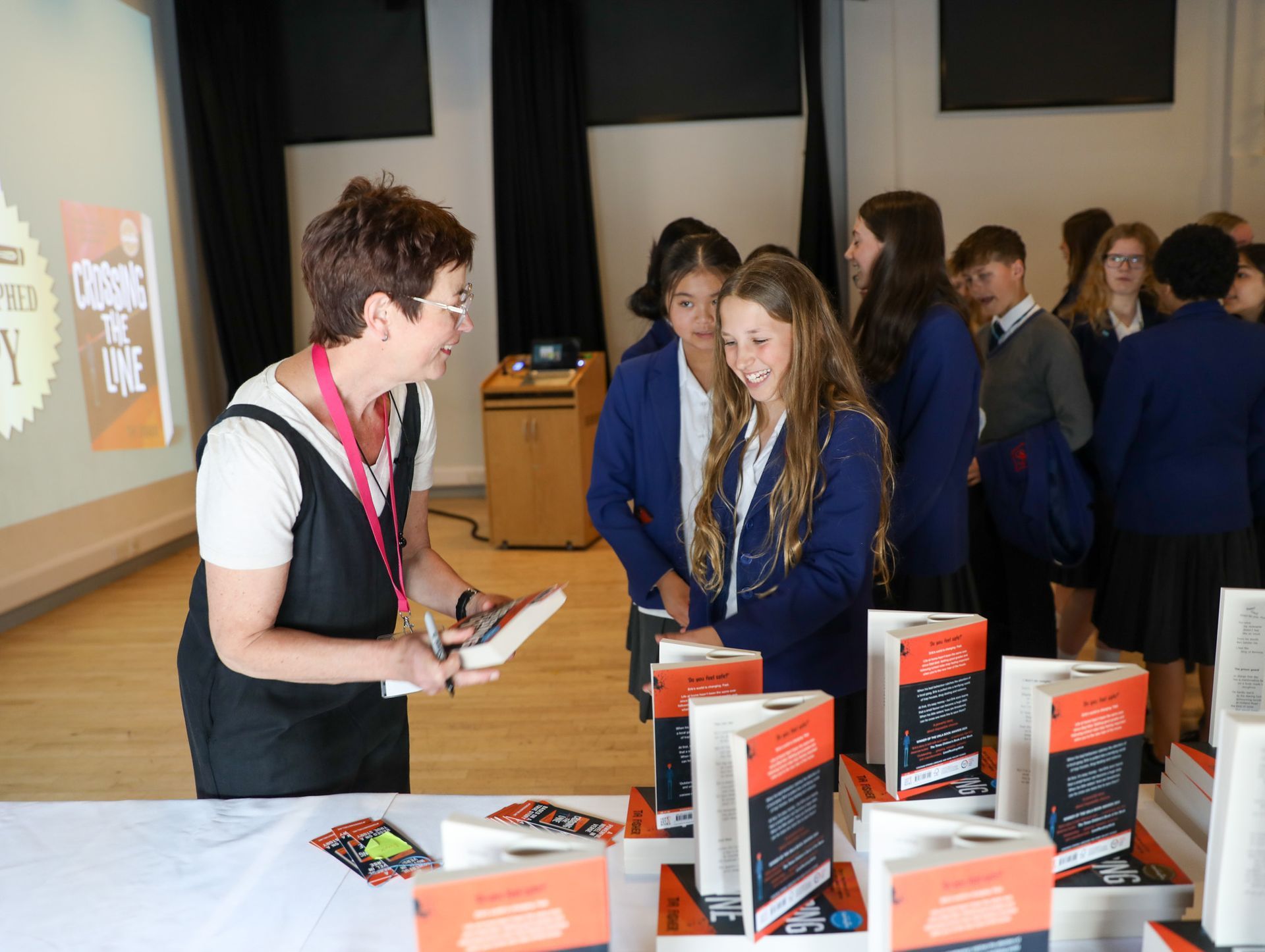 A woman is giving a book to a group of children