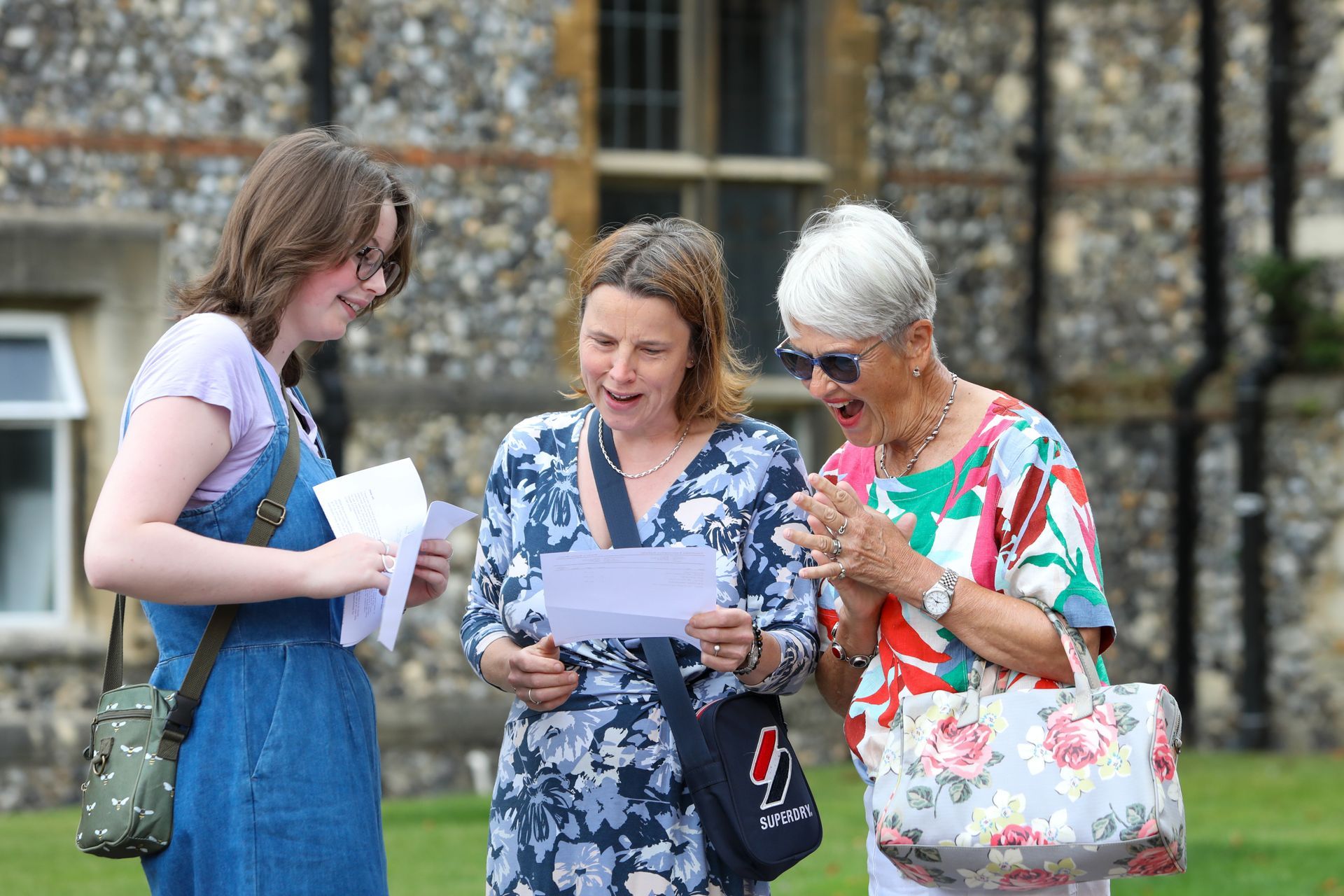 Three women are standing next to each other looking at papers.