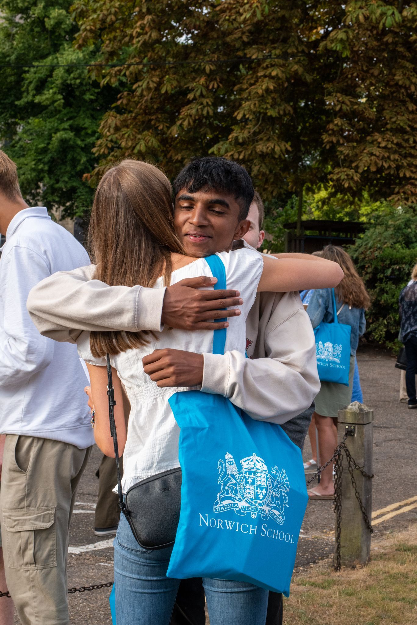 A man is hugging a woman while holding a blue bag.