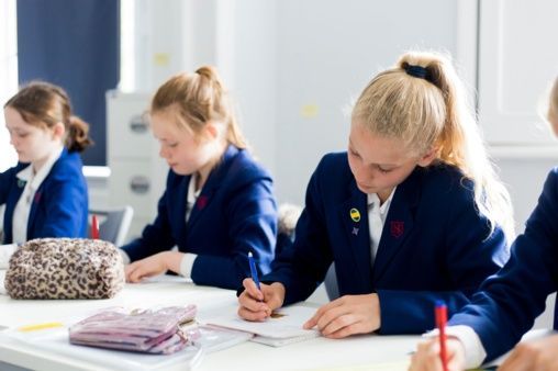 A group of young girls are sitting at a table in a classroom.