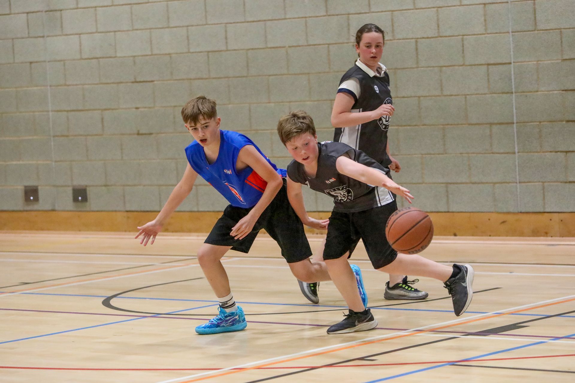 A group of young boys are playing basketball on a court.