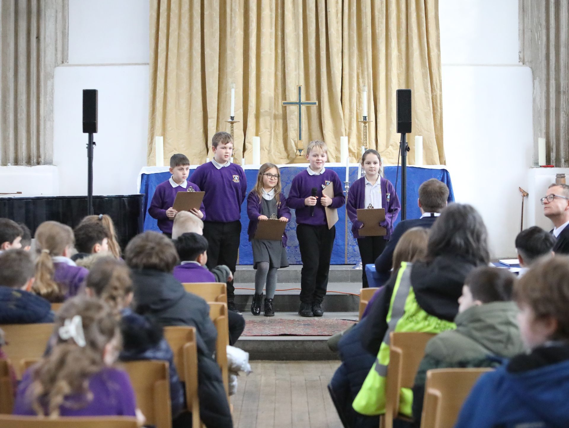 A group of children are singing in front of a crowd in a church.