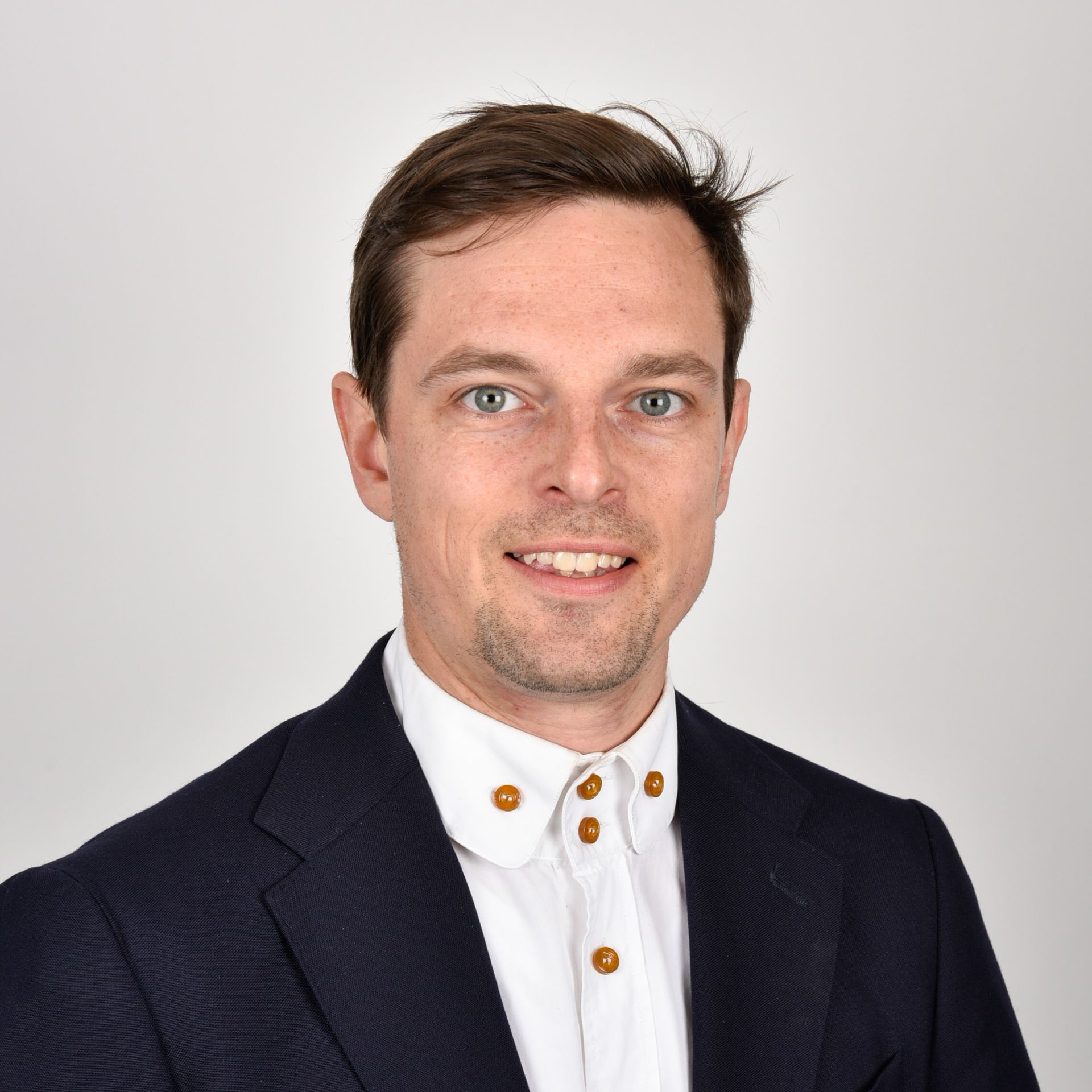 A man in a suit and white shirt is smiling for the camera.