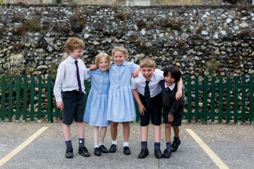 A group of children are posing for a picture in a parking lot.