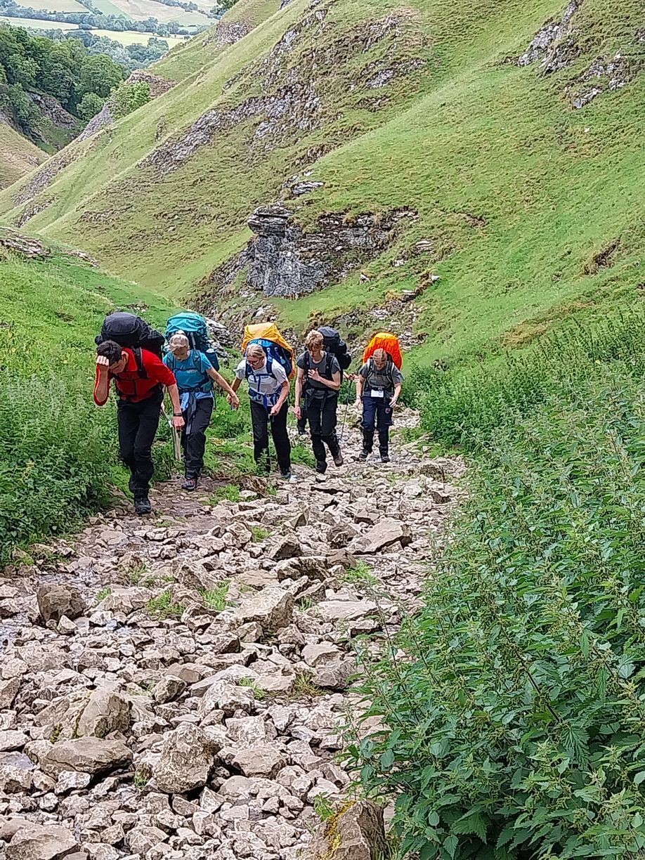 A group of people are hiking up a rocky hill.