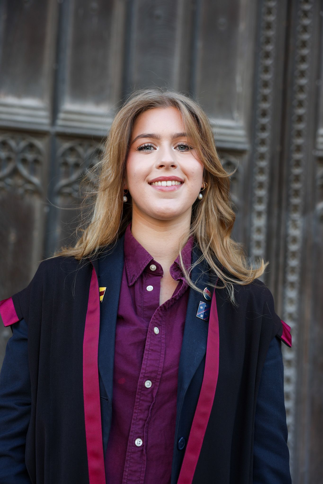 A young woman in a graduation cap and gown is smiling for the camera.