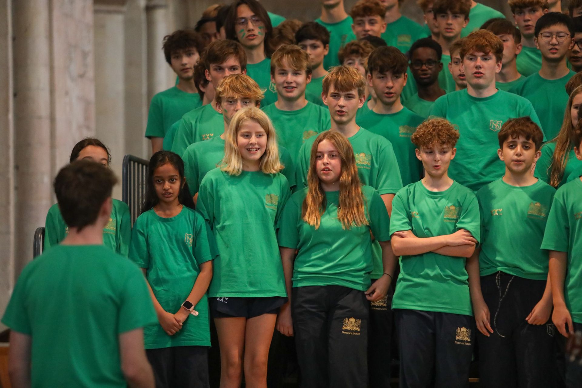A large group of young people wearing green shirts are standing next to each other.