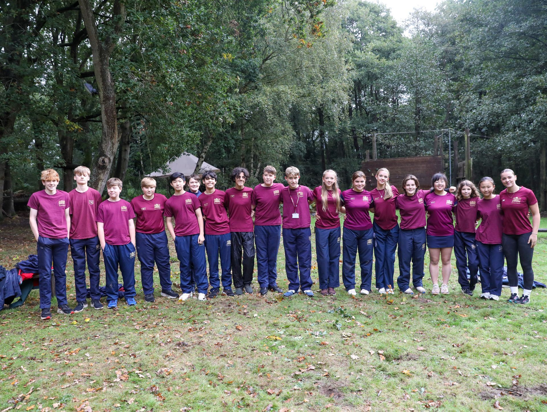 A group of young people are posing for a picture in a field.