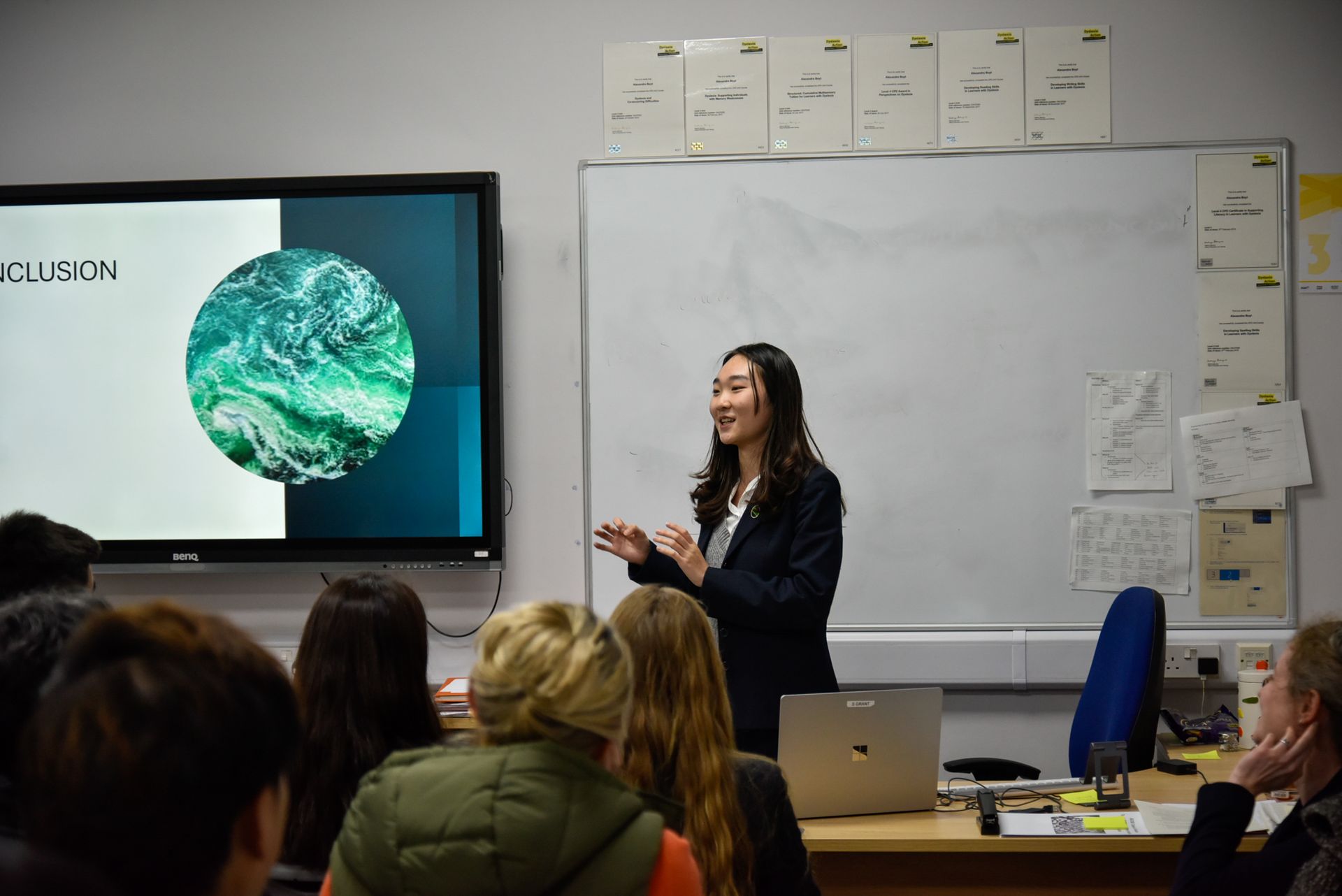 A woman is giving a presentation to a group of people in a classroom.