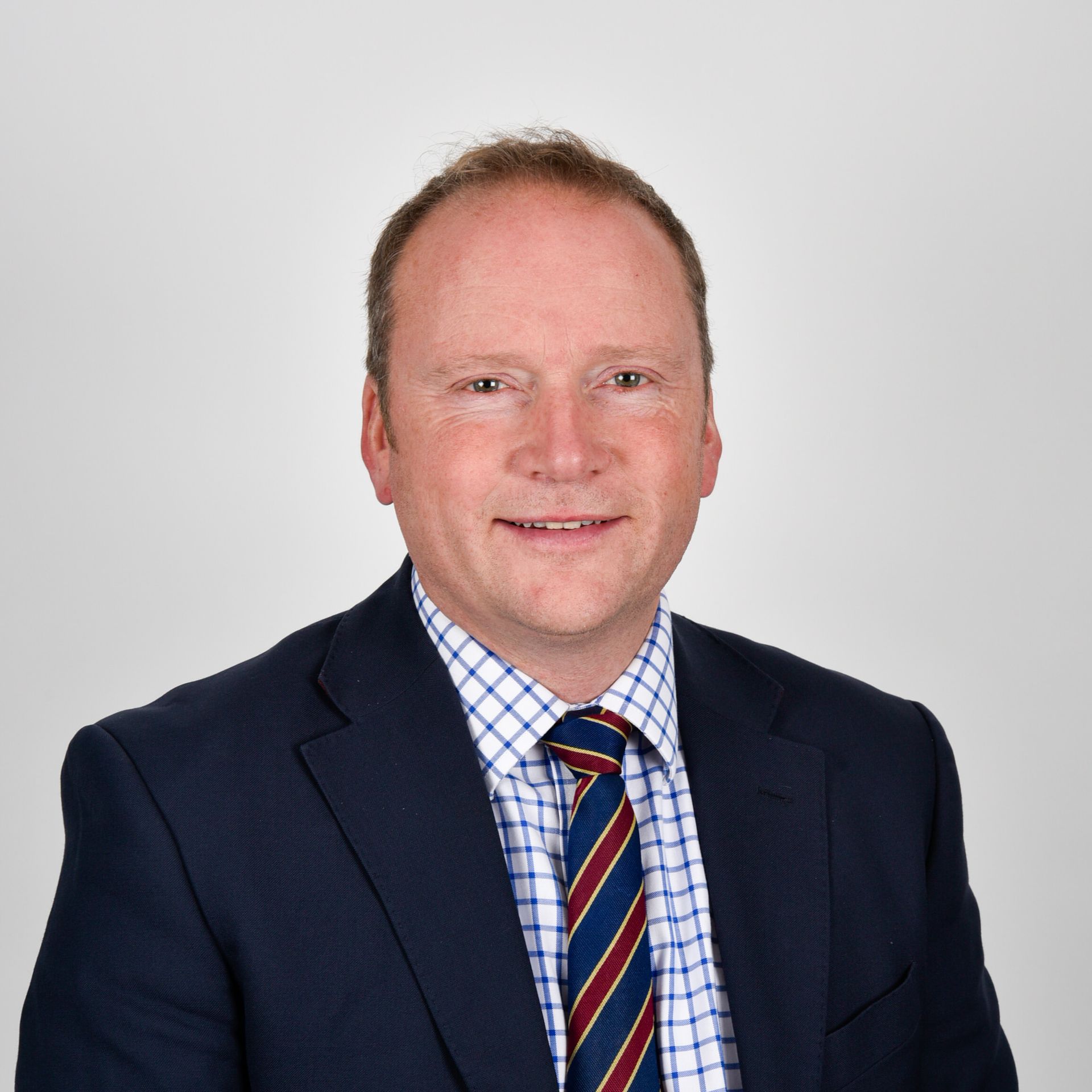 A man in a suit and tie is smiling for the camera