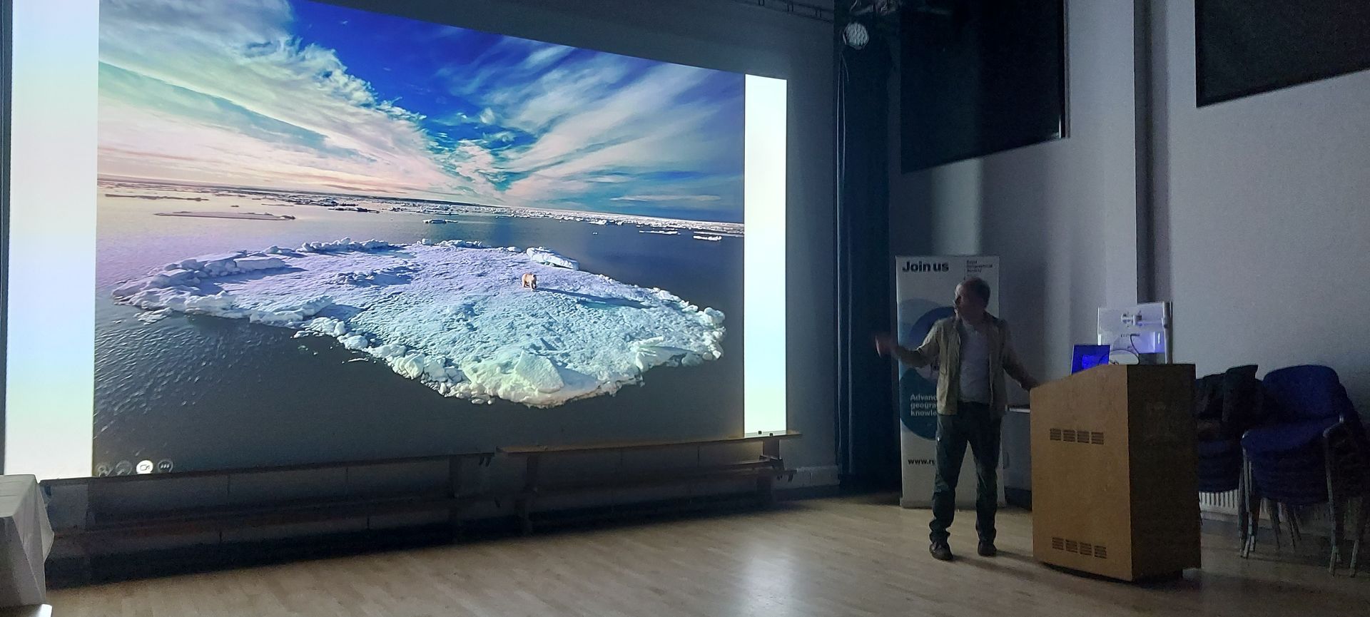 A man is giving a presentation in front of a large screen.
