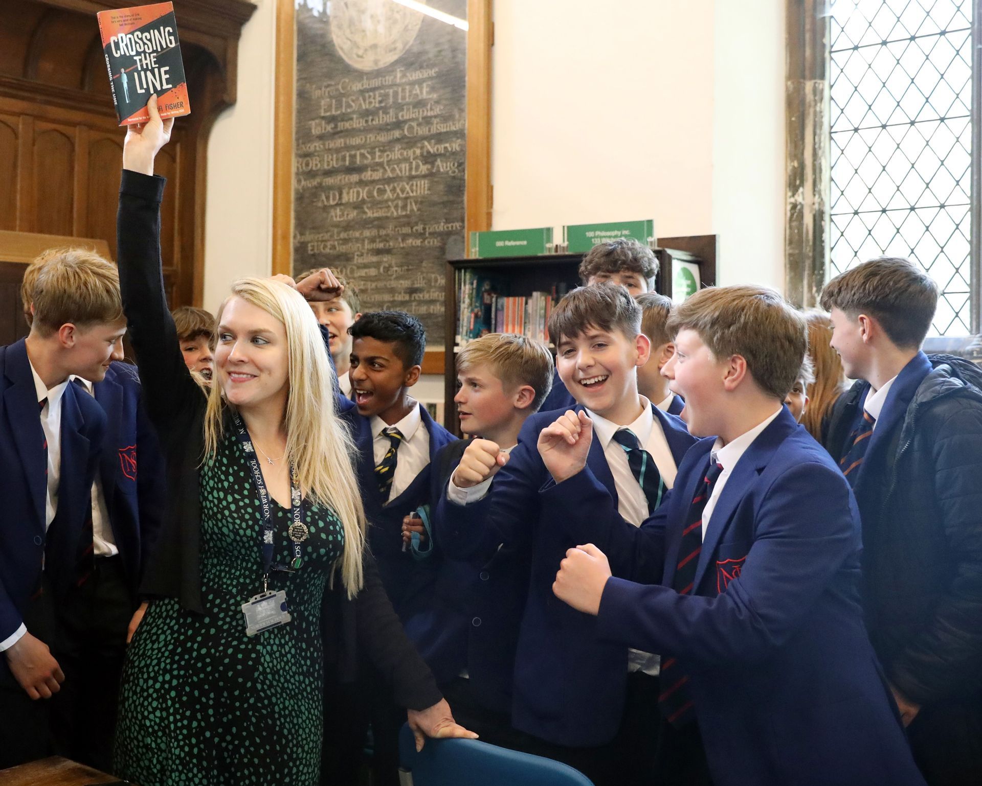 A teacher is holding up a book in front of a group of students.
