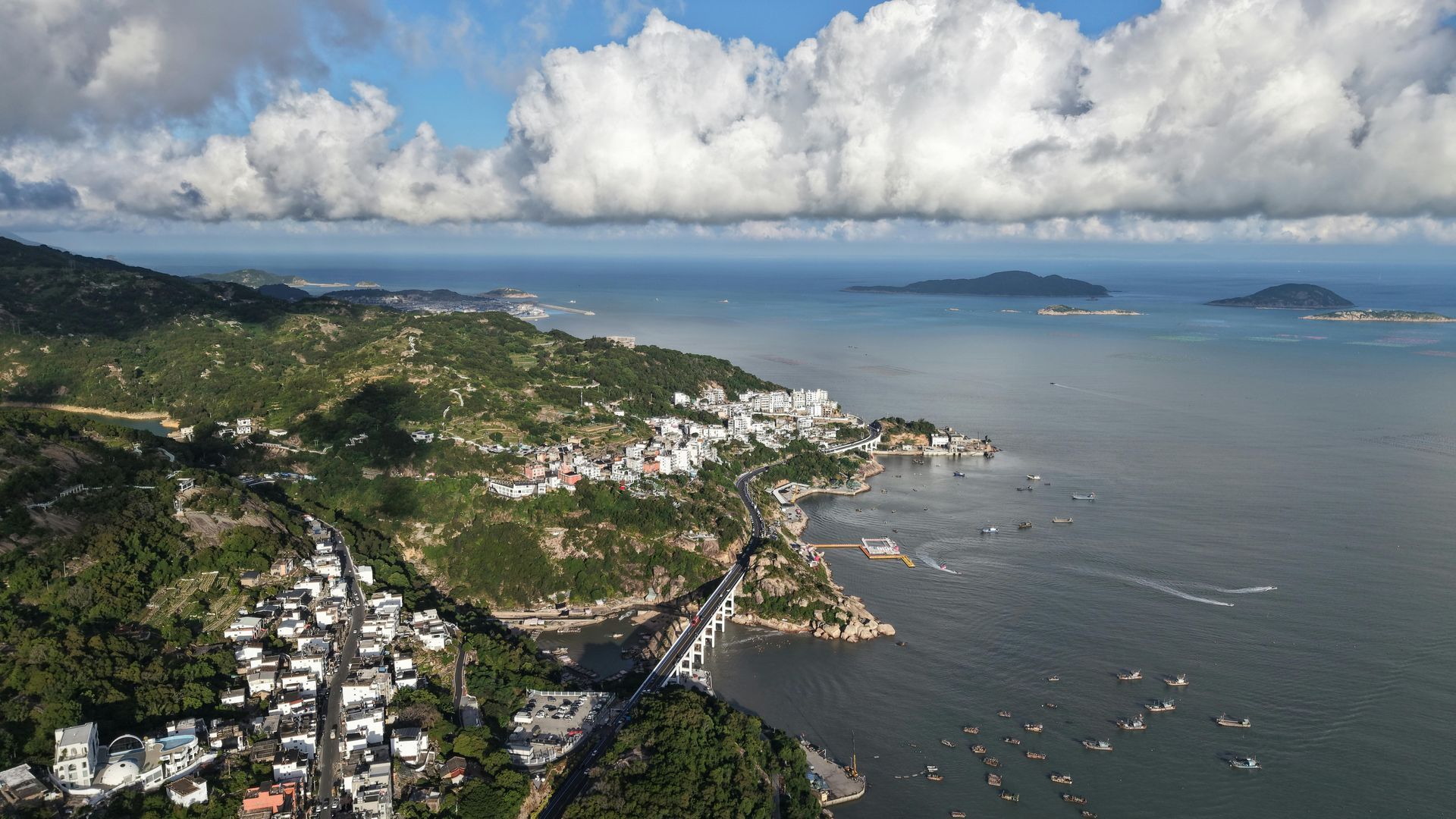 An aerial view of a bridge over a body of water surrounded by mountains.