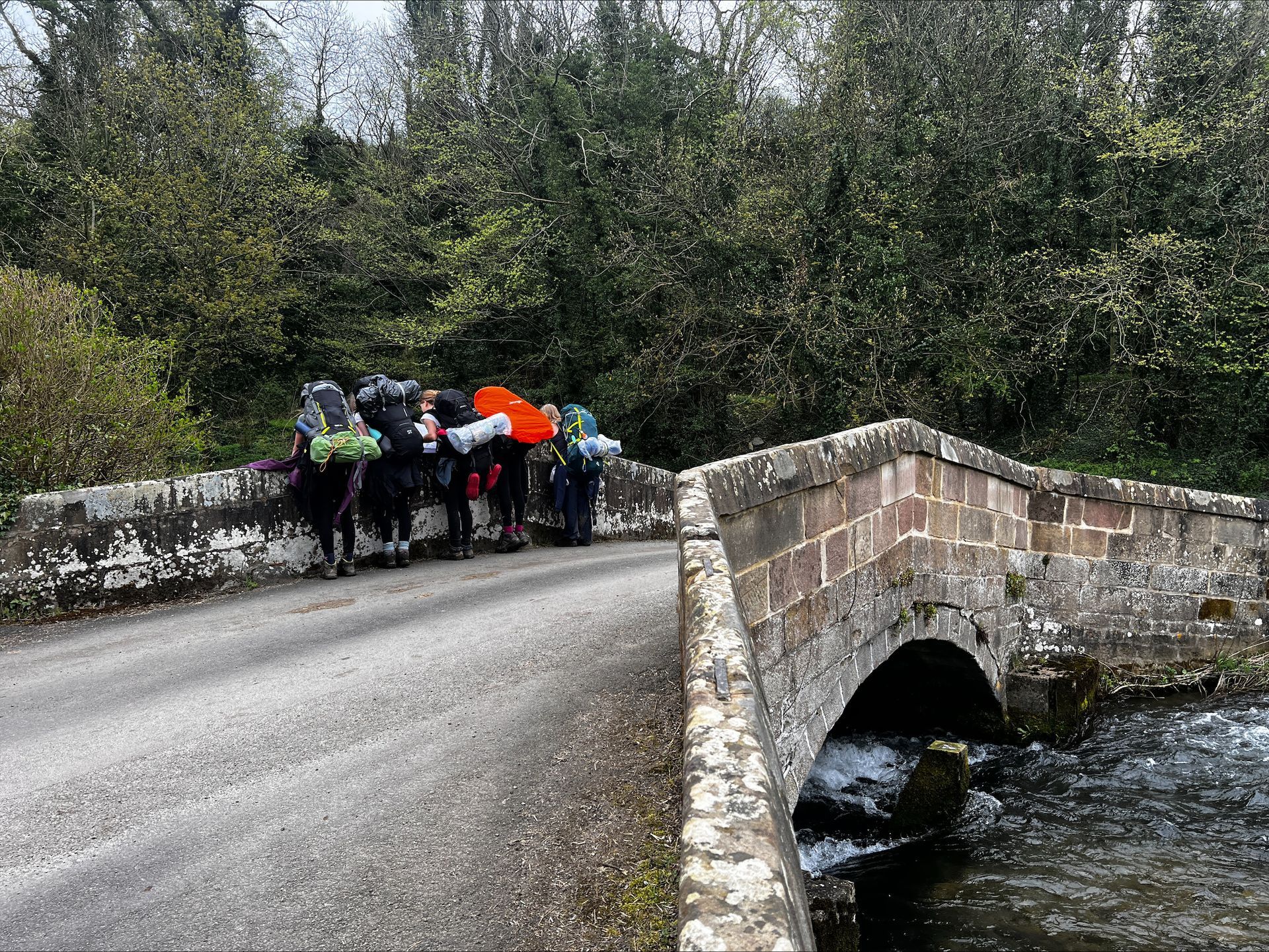 A group of people are standing on a bridge over a river.