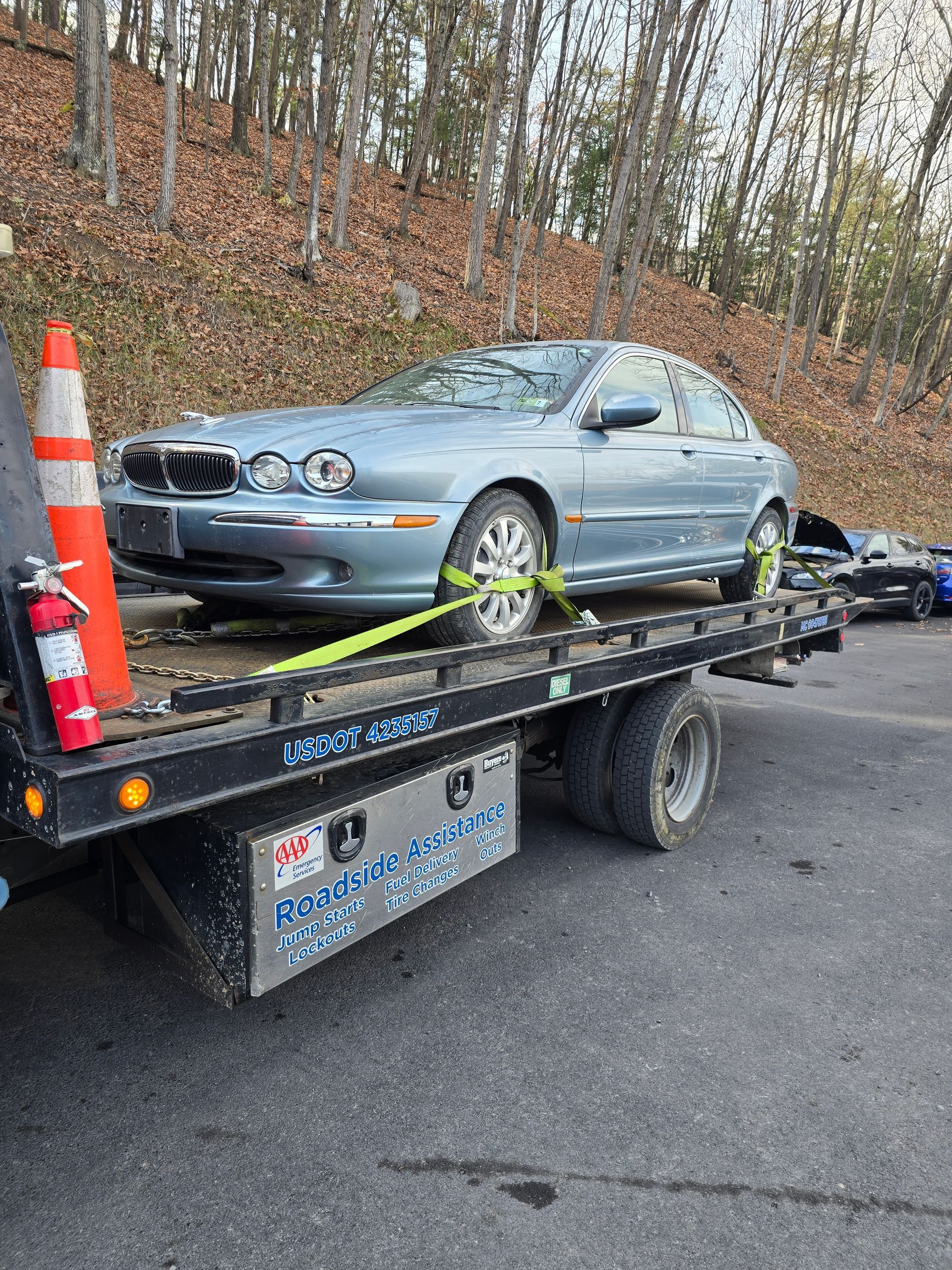 A tow truck is carrying a black car on a highway.