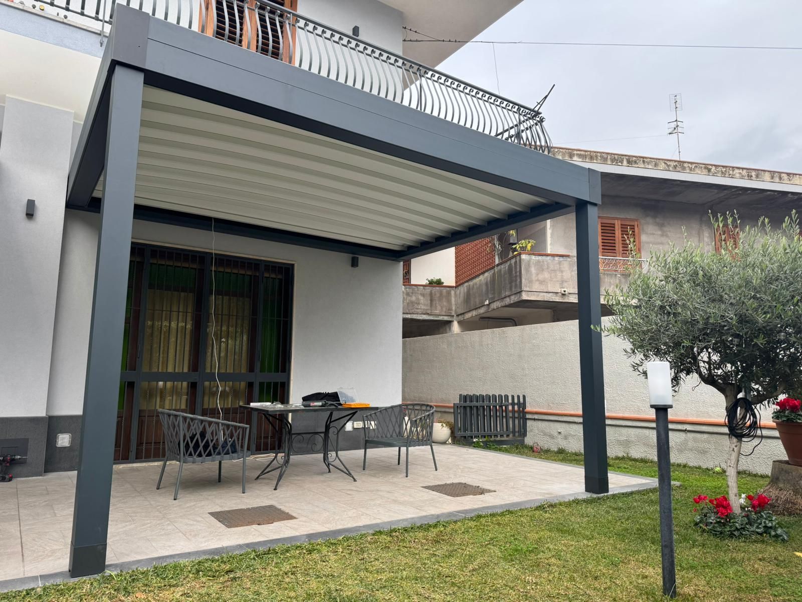Patio coperto con tavolo da pranzo all'aperto, sedie e giardino adiacente alla casa.