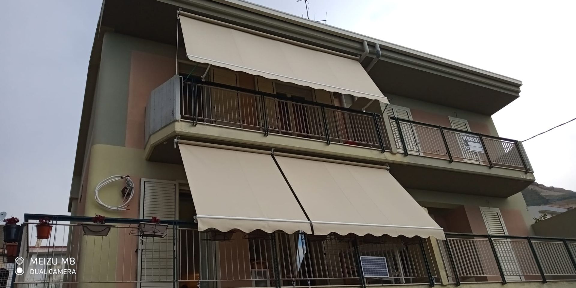 Palazzo residenziale con tende da sole a strisce e balconi, visto dal basso.