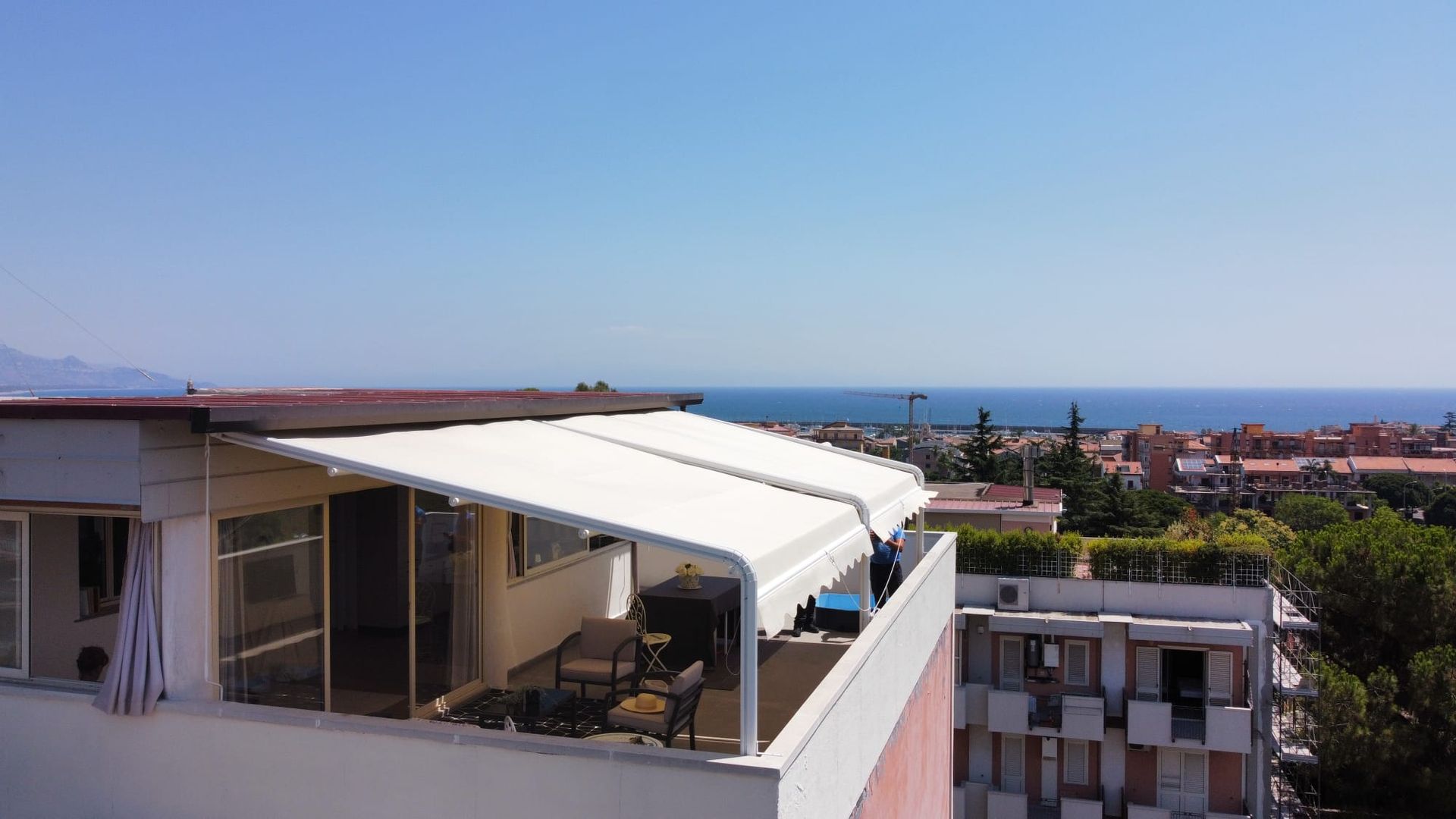 Terrazza sul tetto con tettoia bianca con vista sulla città e sul mare.