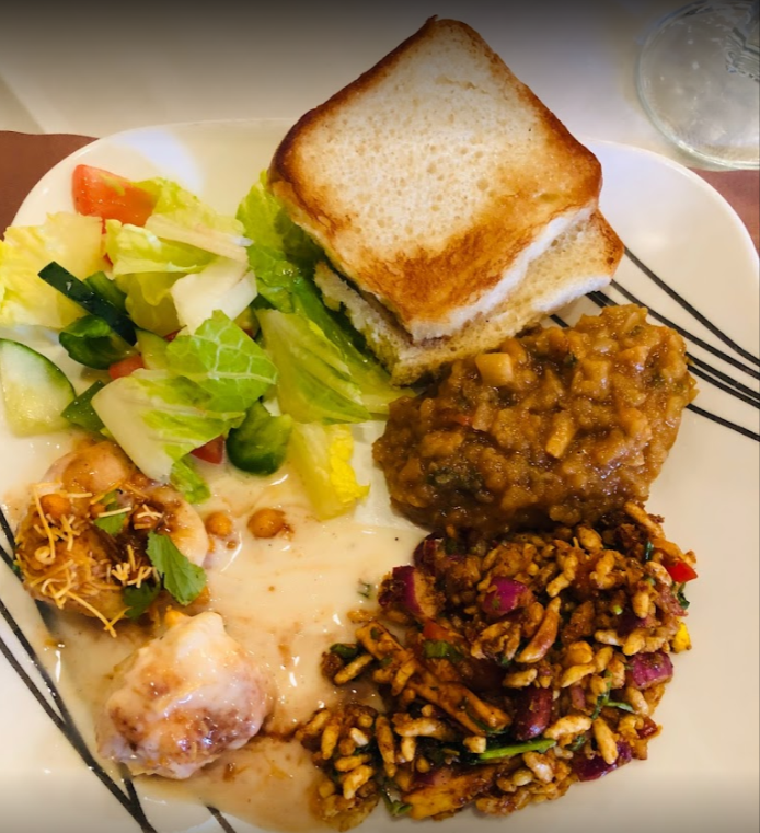 Plate of food with a toasted sandwich, salad, and various dishes.