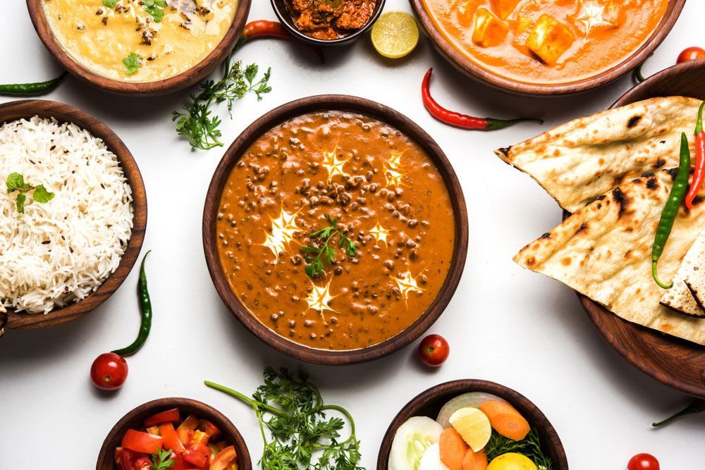 Indian food spread with bowls of dal, rice, curries, and naan bread.
