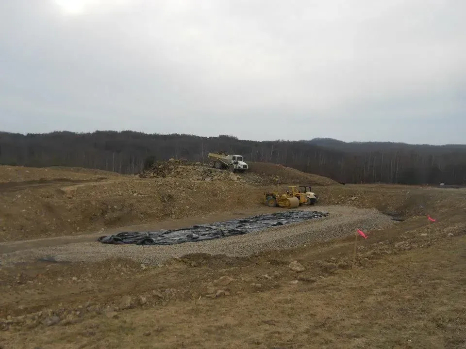 Construction site with earth-moving equipment on a dirt hill under an overcast sky