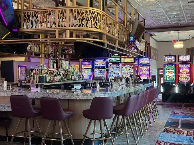 Upscale casino bar with purple stools, mirrored counter, and colorful slot machines in the background