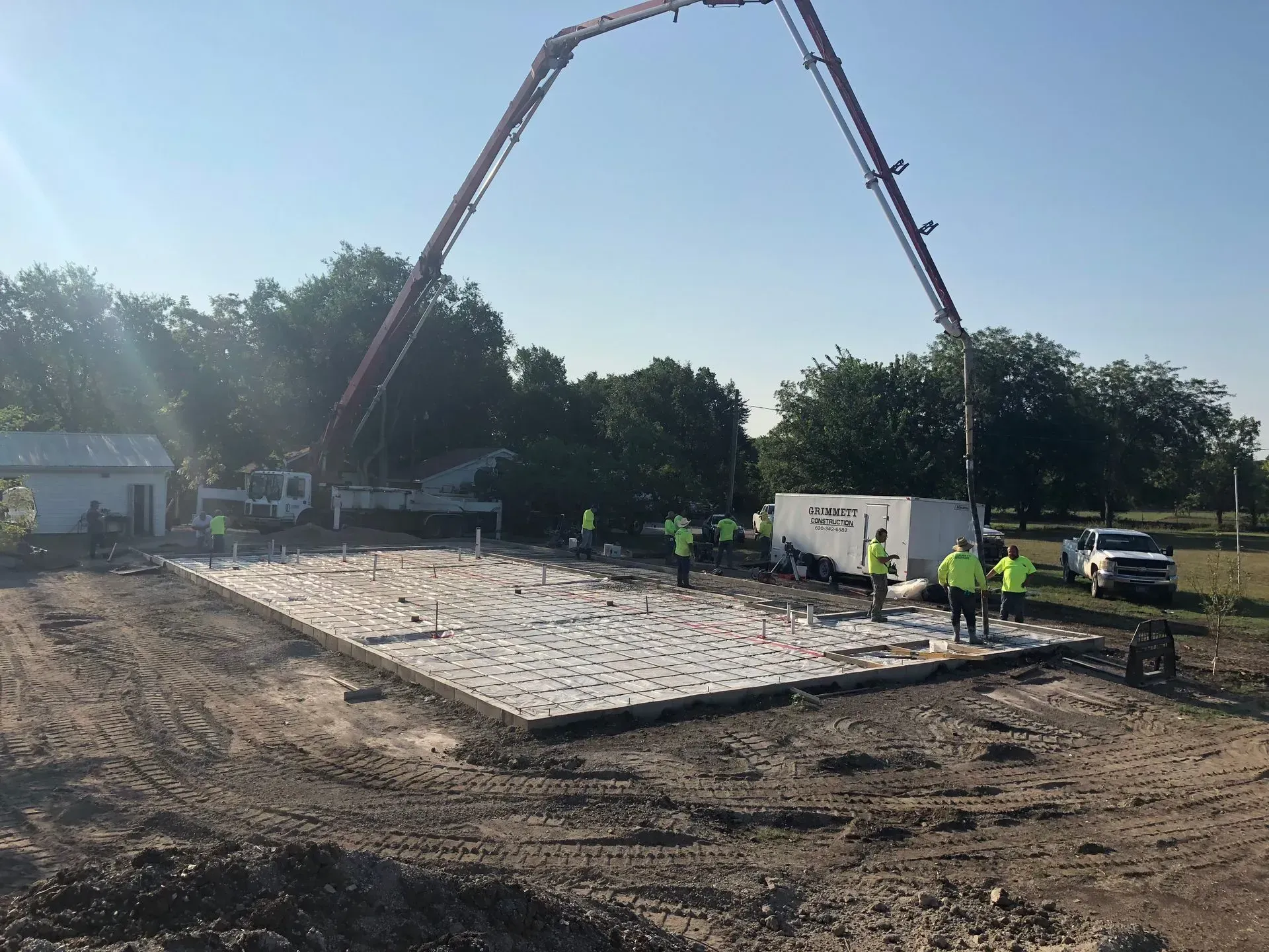 Concrete slab being poured at a construction site by a pump truck and workers in safety vests
