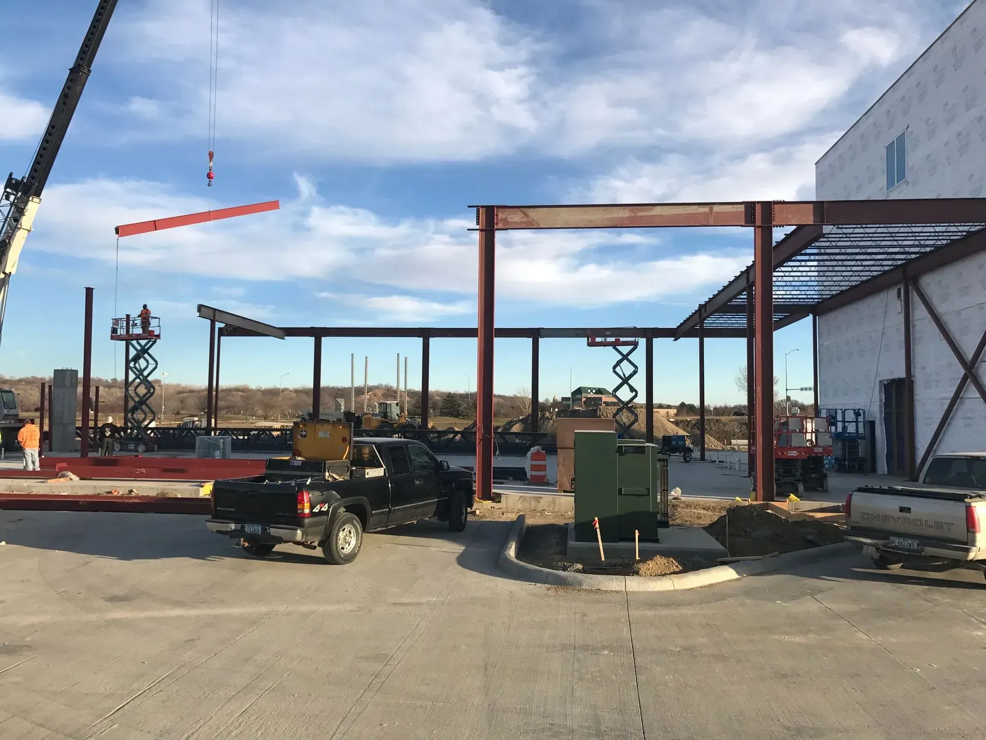 Construction site with steel frame, parked utility vehicle, and blue sky overhead