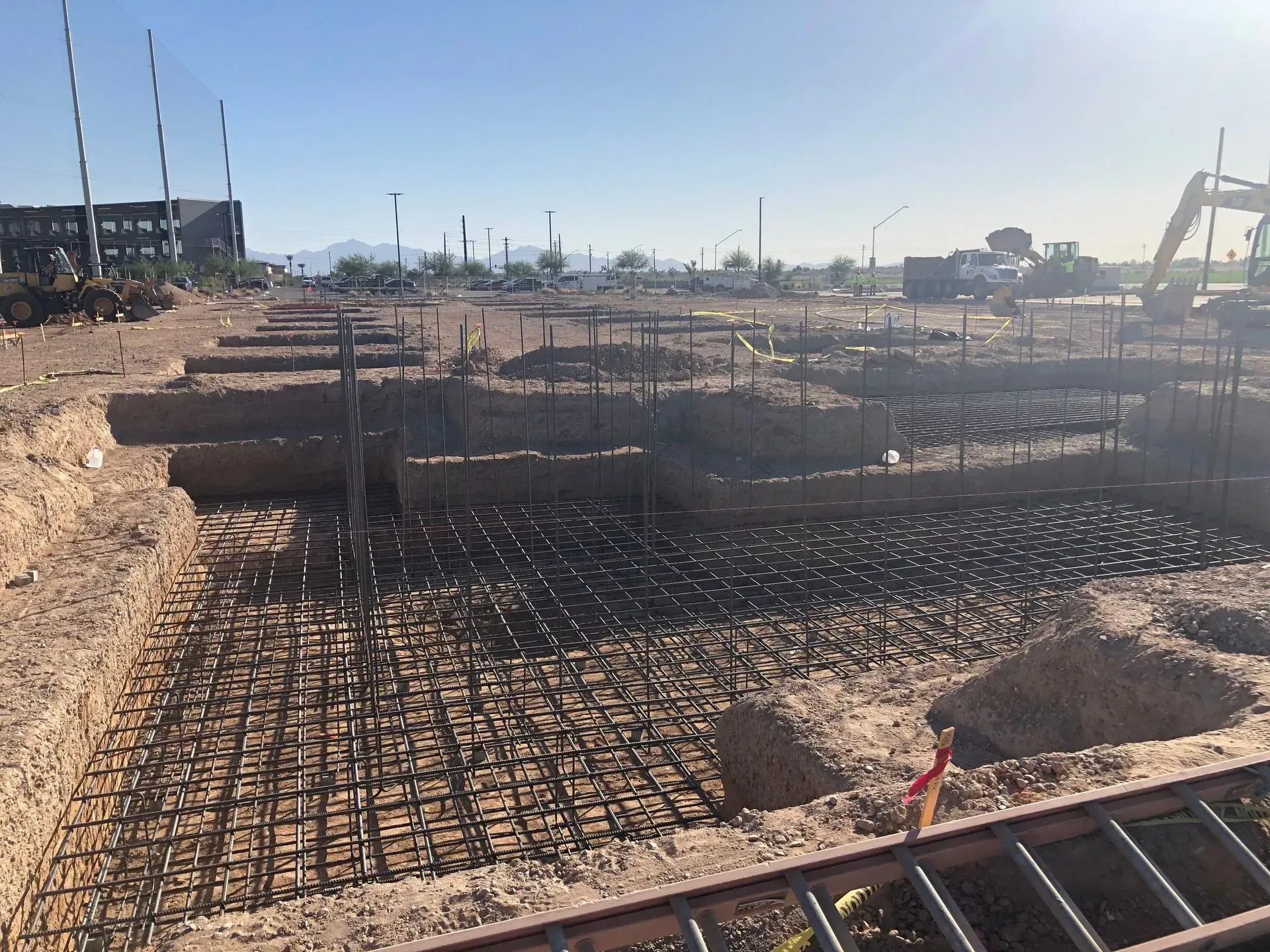 Construction site with rebar foundations and trenches under bright sunlight