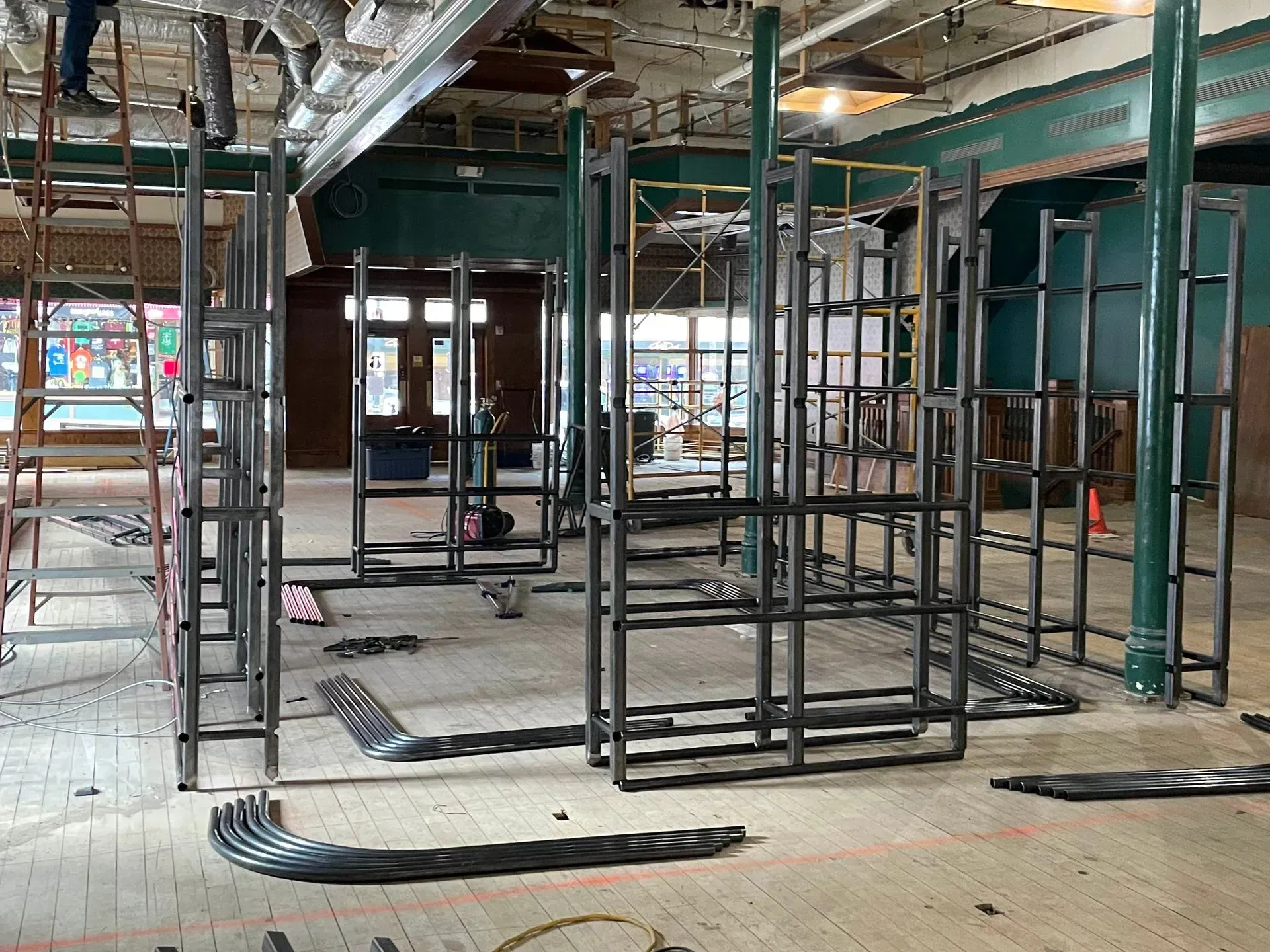Empty construction interior with metal framing, scaffolding, and exposed ceiling work.