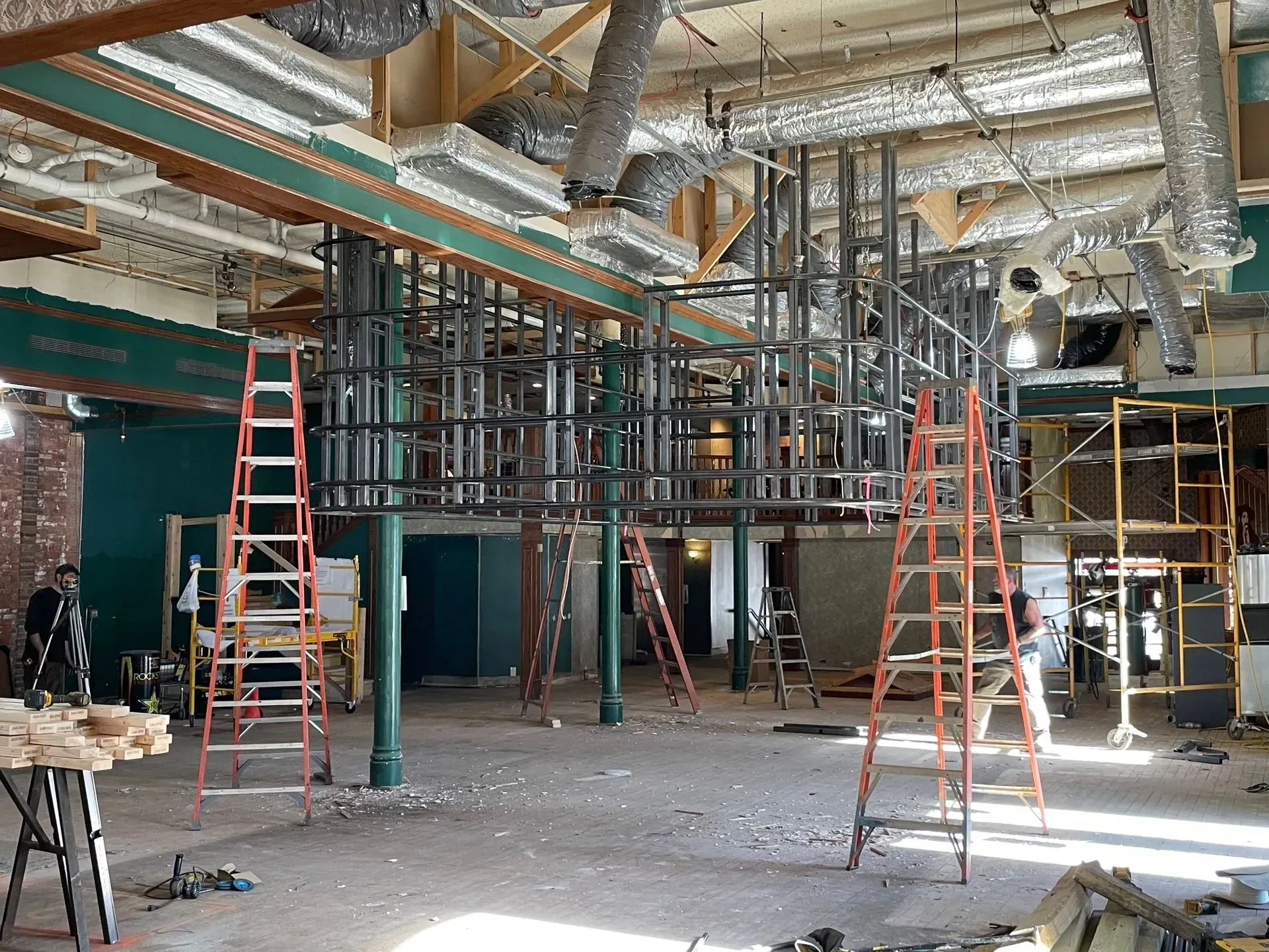 Construction site interior with scaffolding, ladders, exposed ductwork, and debris-covered floor