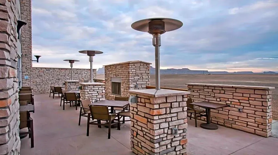 Outdoor rooftop patio with stone tables and tall heaters overlooking a cloudy landscape