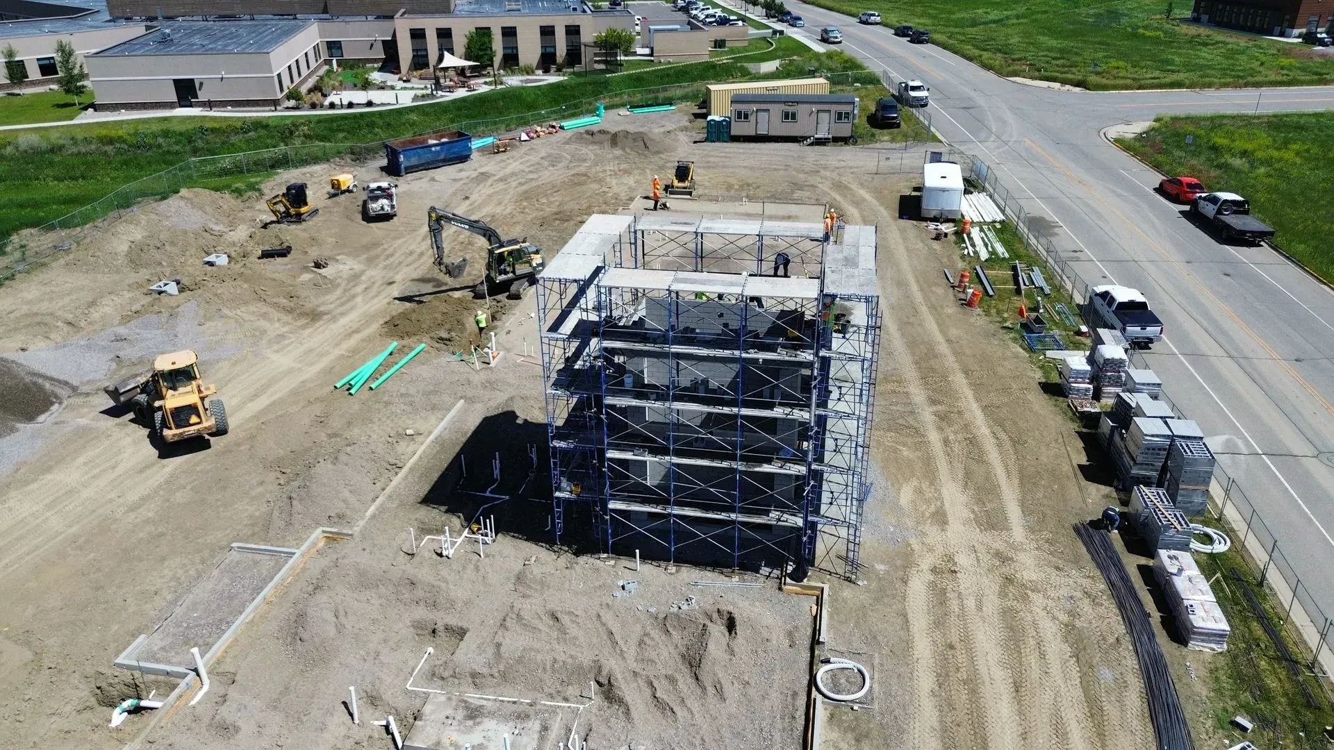 Aerial view of a construction site with a partially built multi-story building and heavy equipment nearby