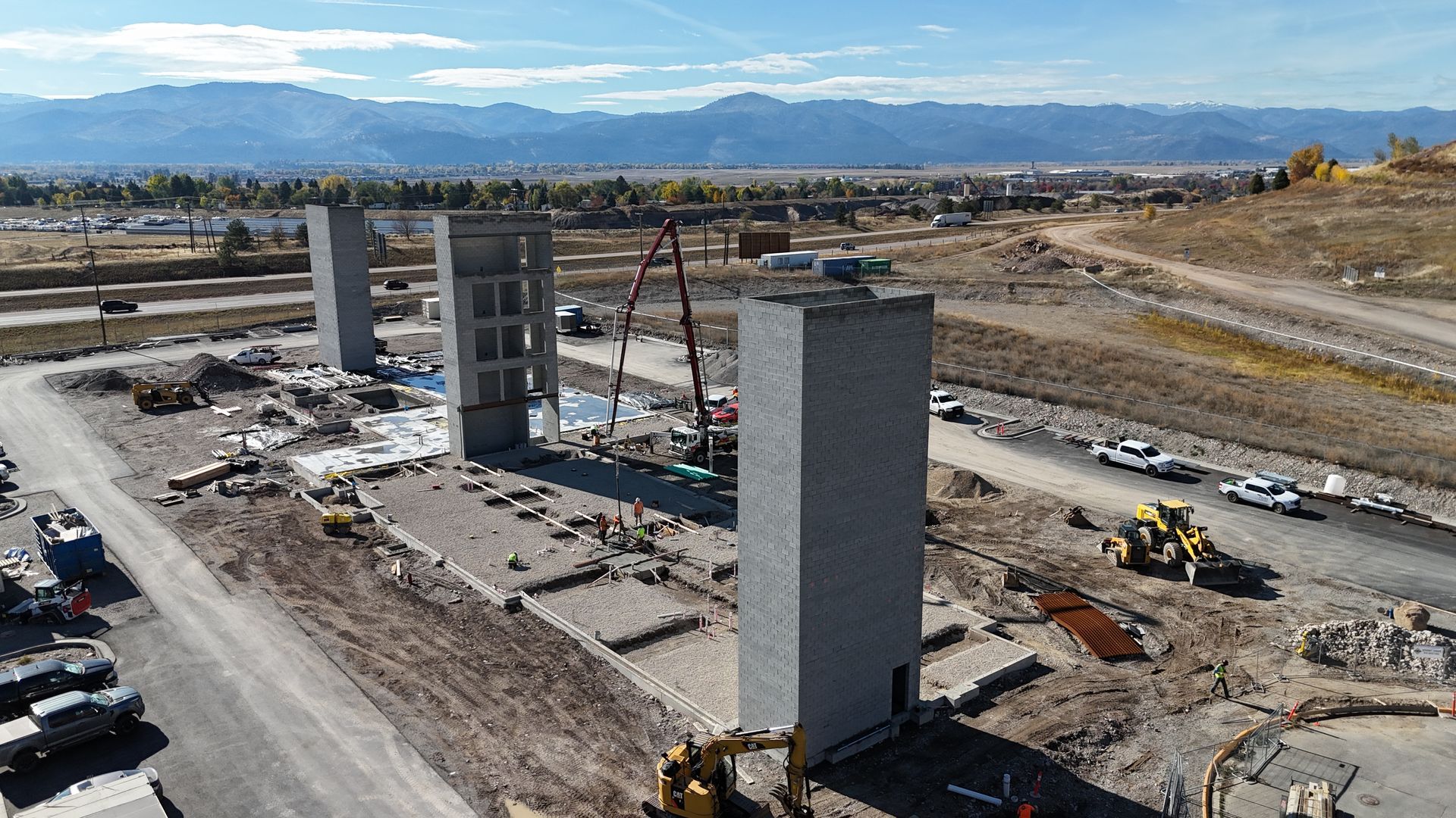 Construction site with two tall concrete structures, cranes, and equipment in a