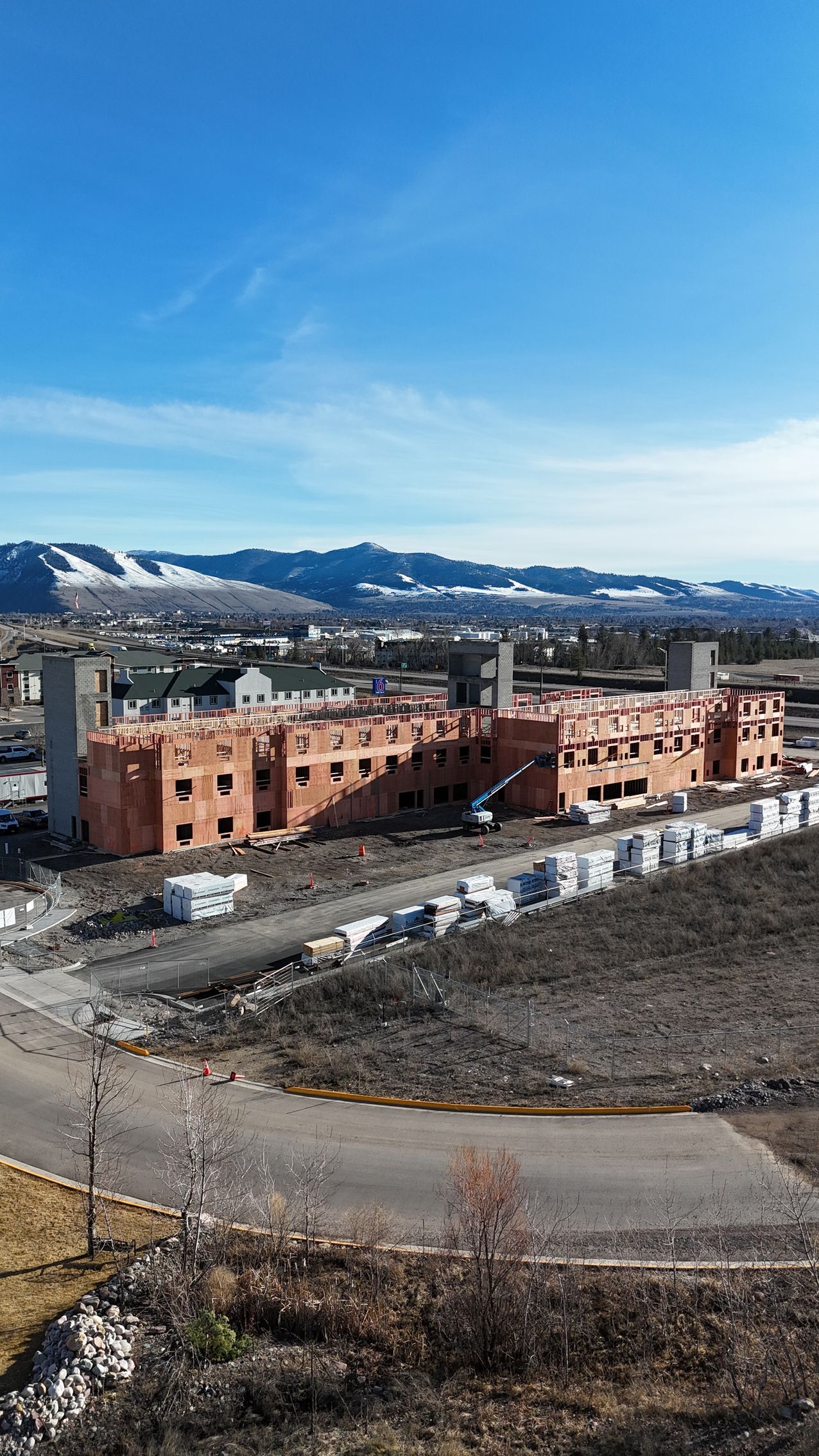 Partly built brick housing complex with mountains and blue sky in the background