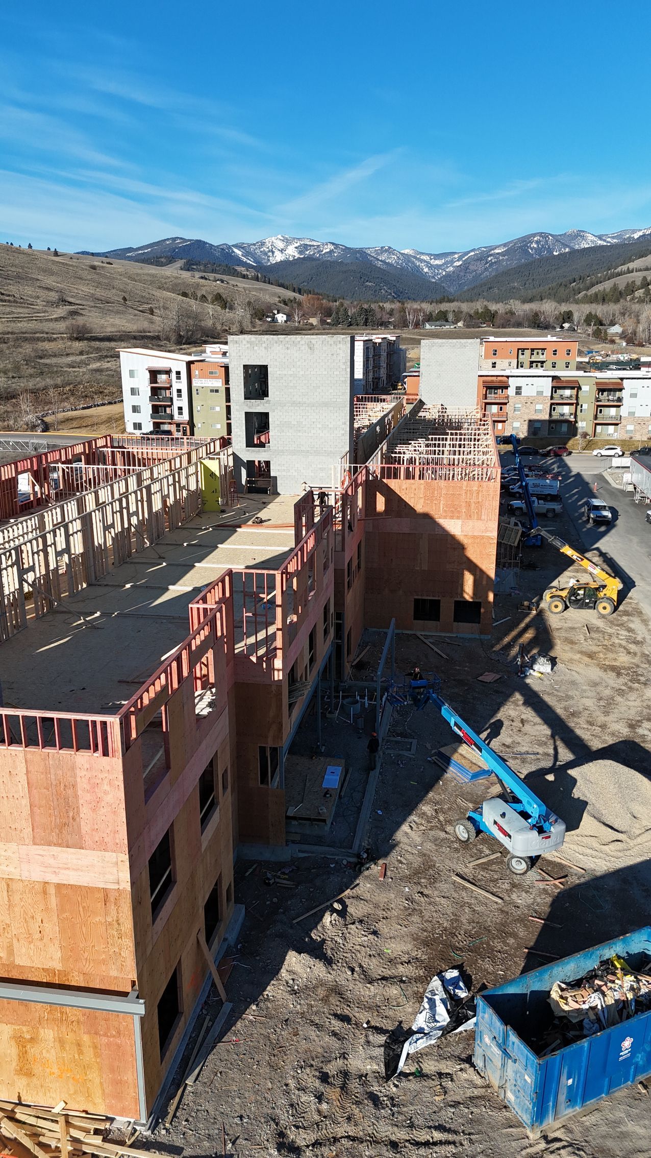 Construction site with brick apartment buildings under construction and mountains in the background