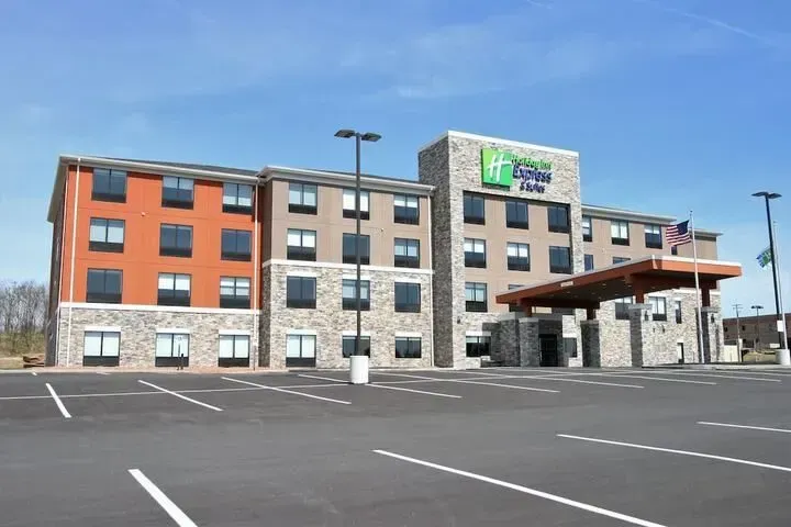 Modern hotel building with gray and orange exterior beside an empty parking lot under a blue sky