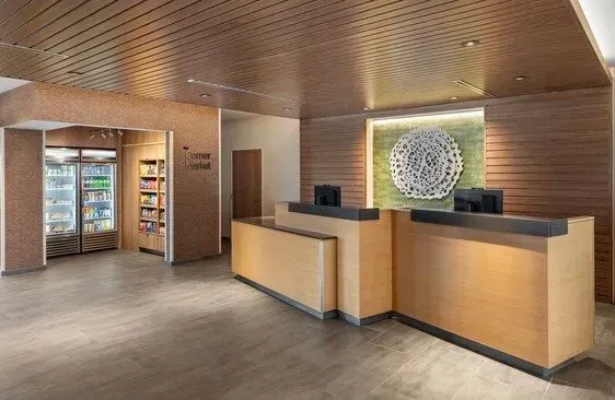 Modern hotel lobby with wood-paneled reception desk, vending machines, and circular wall art
