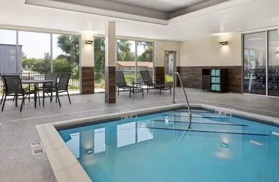 Indoor swimming pool in a bright, modern lounge with glass walls and patio seating