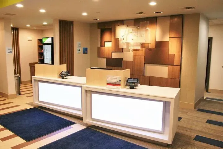Modern hotel lobby reception with two white front desks and warm wood-paneled walls