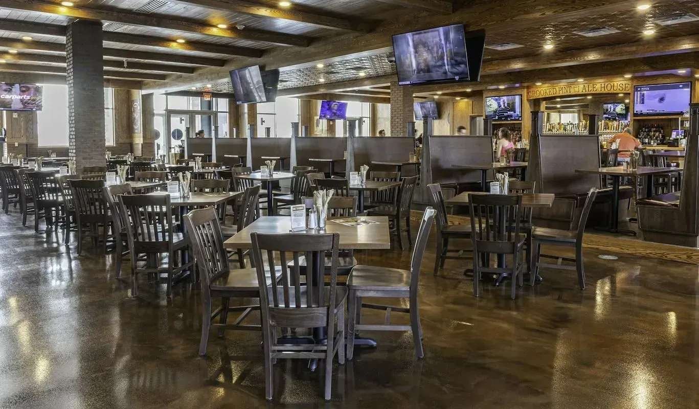 Empty sports bar with tables, stools, shiny floor, and multiple TVs behind the counter.