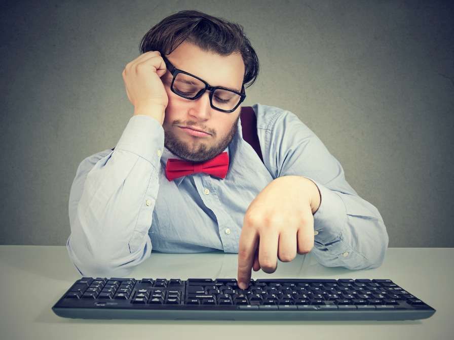 Demotivierter Mann, der auf einer Tastatur lustlos klickt